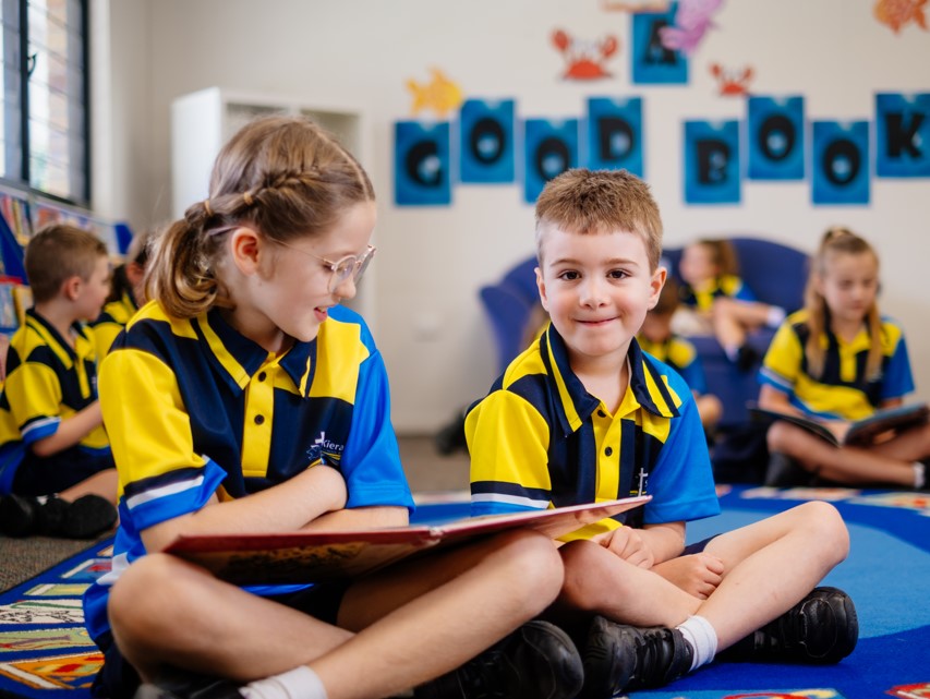 Students in school uniforms sitting on a carpet reading together in a classroom