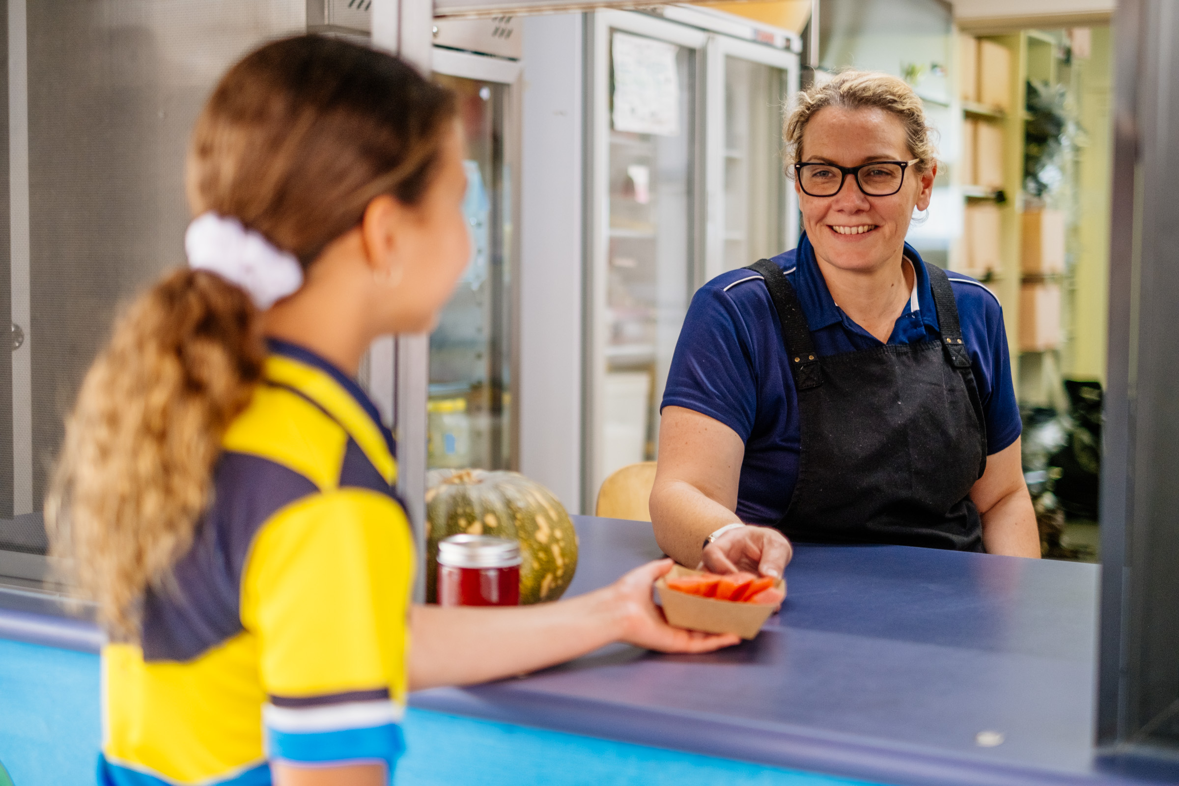 Adult serving food to a student at a school tuckshop counter